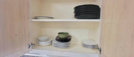 A cabinet with shelves holding plates and bowls.