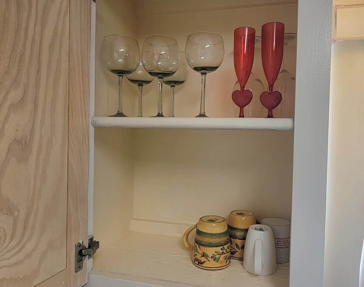 A cabinet with wine glasses and mugs.