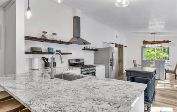 A modern kitchen with a marble countertop, stainless steel appliances, and a large island.
