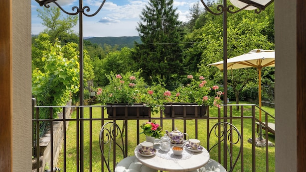 Une terrasse de jardin avec une table préparée pour le thé, entourée de rampes en métal et de plantes en pot.
