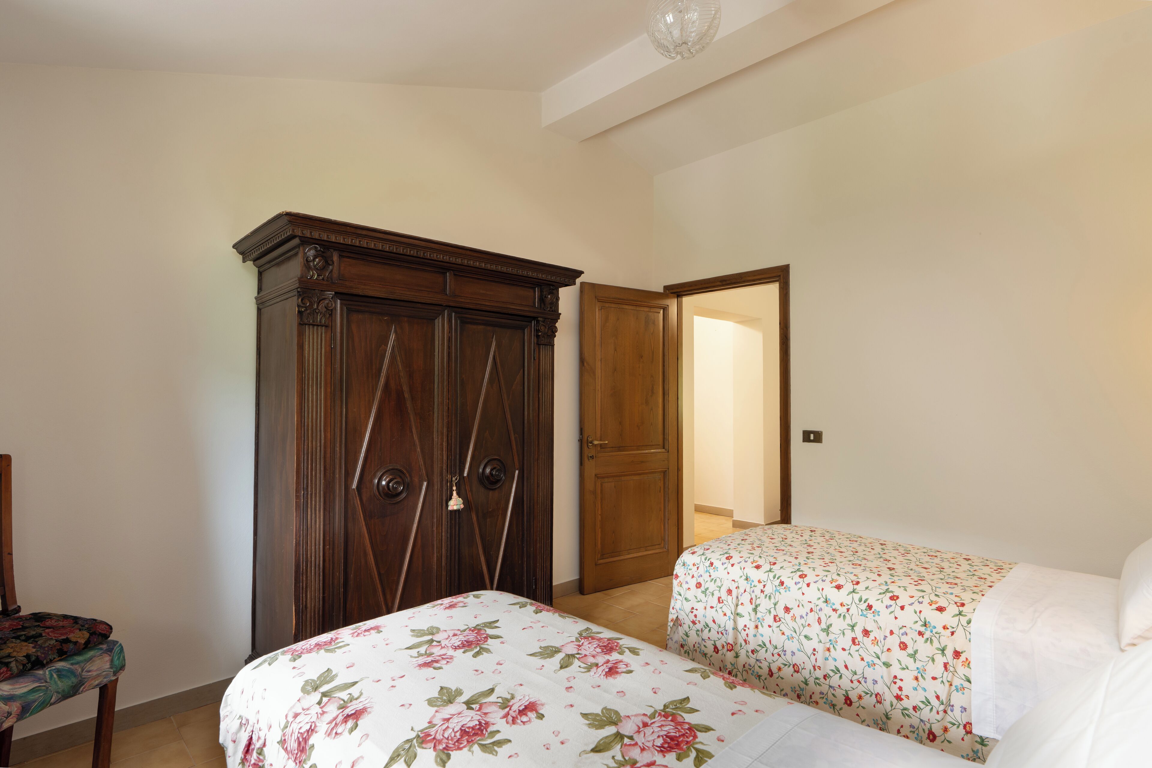 Un dormitorio con dos camas, un armario de madera y una silla.