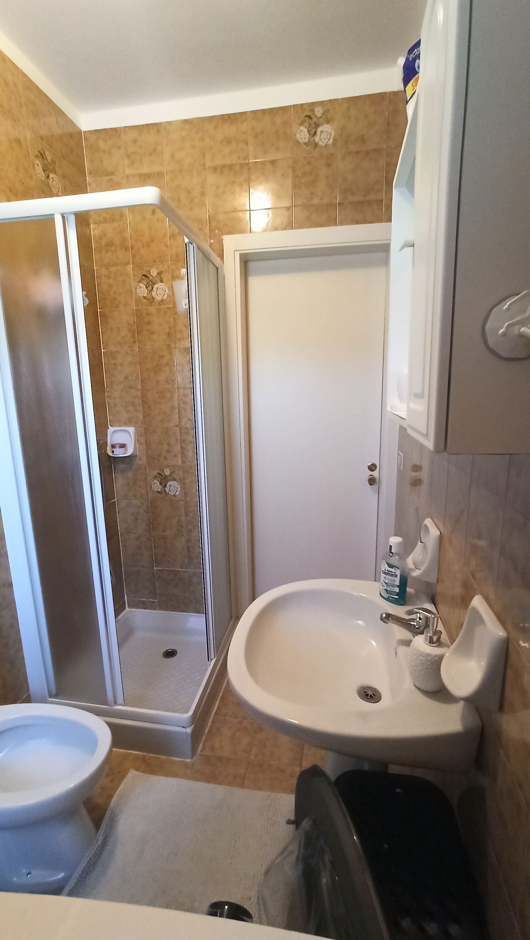 A bathroom with a shower, toilet, sink, and a cabinet.