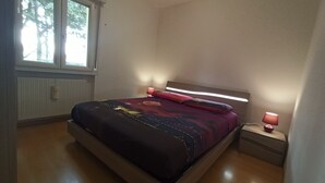 A bedroom with a bed, bedside tables, and a window. - APARTMENT AVIANO (Aviano)