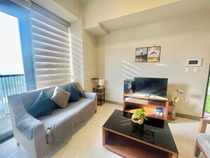 Ein Wohnzimmer mit einer Couch, einem Couchtisch, einem Fernseher und einem Wandlautsprecher.