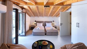 A modern hotel room with two beds, a dining area with breakfast, and a large wardrobe.