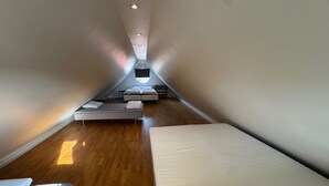 A modern, narrow attic bedroom with wooden flooring, a skylight, and a bed with a white mattress. - Modern 1-bedroom Apartment for 6 Near Kristianstad (Fjalkinge)