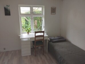 A room with a desk, chair, and bed.
