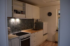 A kitchen with white cabinets, a stove, a sink, and a radio.