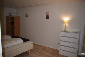 A bedroom with a bed, a wardrobe, a dresser, and a wall-mounted lamp. - Villa in a cozy village in Southern Jutland (Tønder)