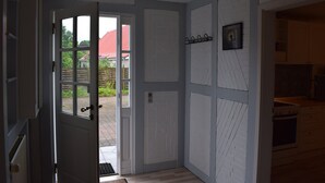 Une cuisine avec des meubles blancs, une cuisinière et une porte donnant sur l’extérieur.