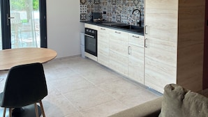 A modern kitchen with wooden cabinets, a black countertop, and a tiled backsplash.