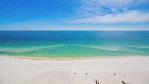 Ein weiter Sandstrand mit klarem türkisblauem Wasser.