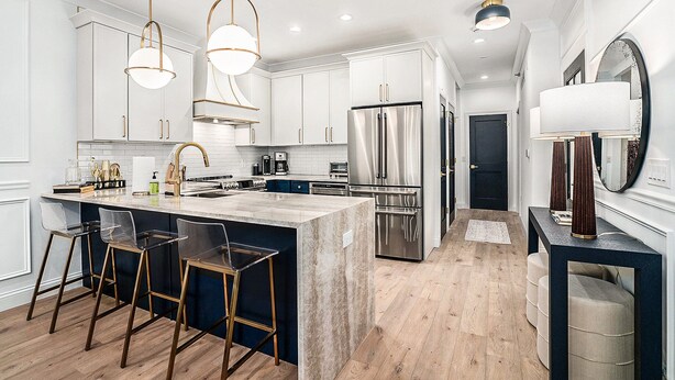 A modern kitchen with white cabinets, stainless steel appliances, and a central island with bar stools.