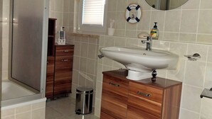 A bathroom with a shower, a sink, a toilet, and a vanity with drawers.