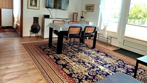A dining area with a table, chairs, a rug, a television, and artwork on the walls.