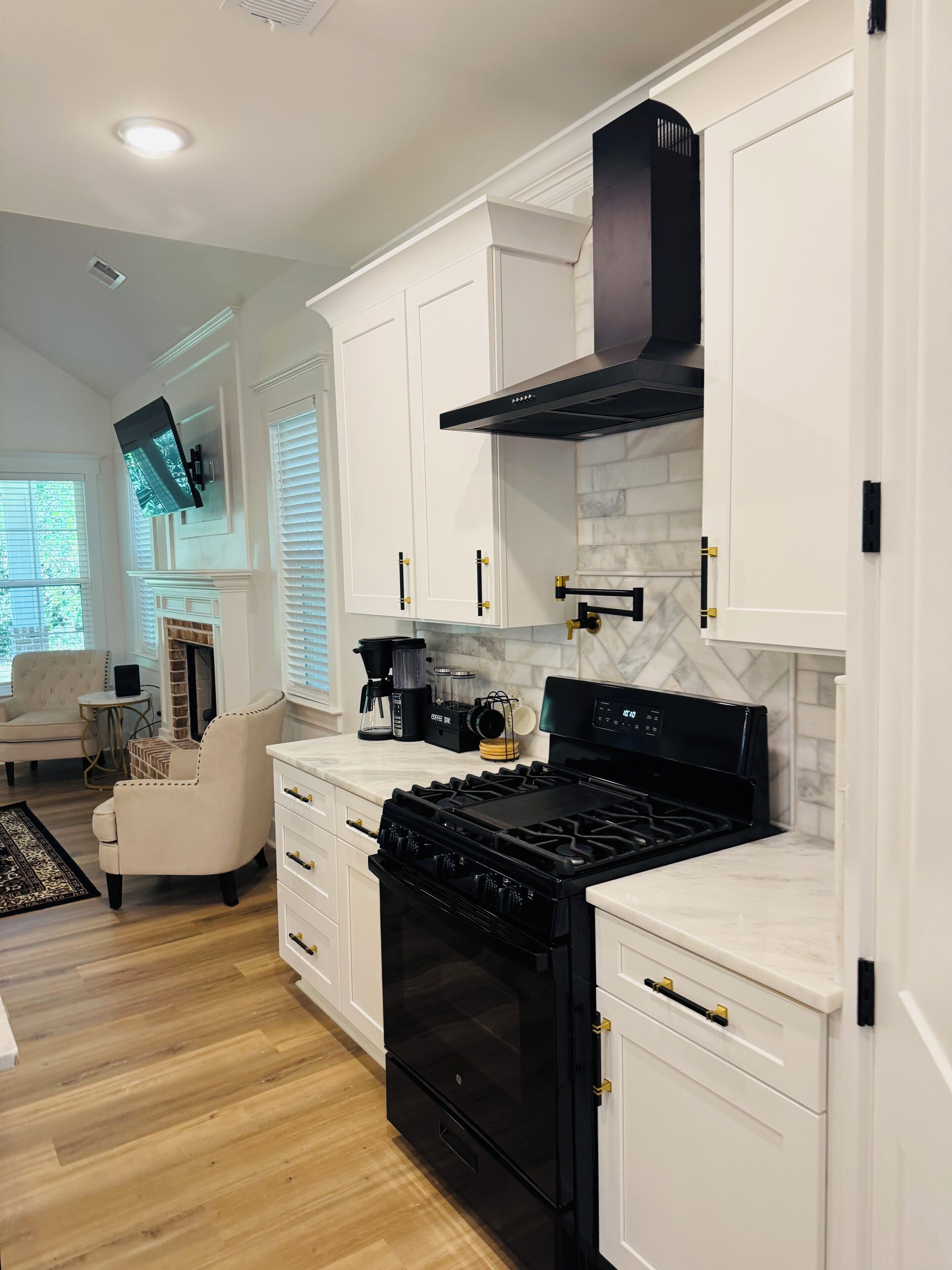 A modern kitchen with white cabinetry, a black stove, and a marble backsplash.