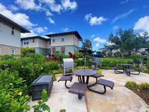 A patio area with outdoor seating, a barbecue grill, and a trash bin.
