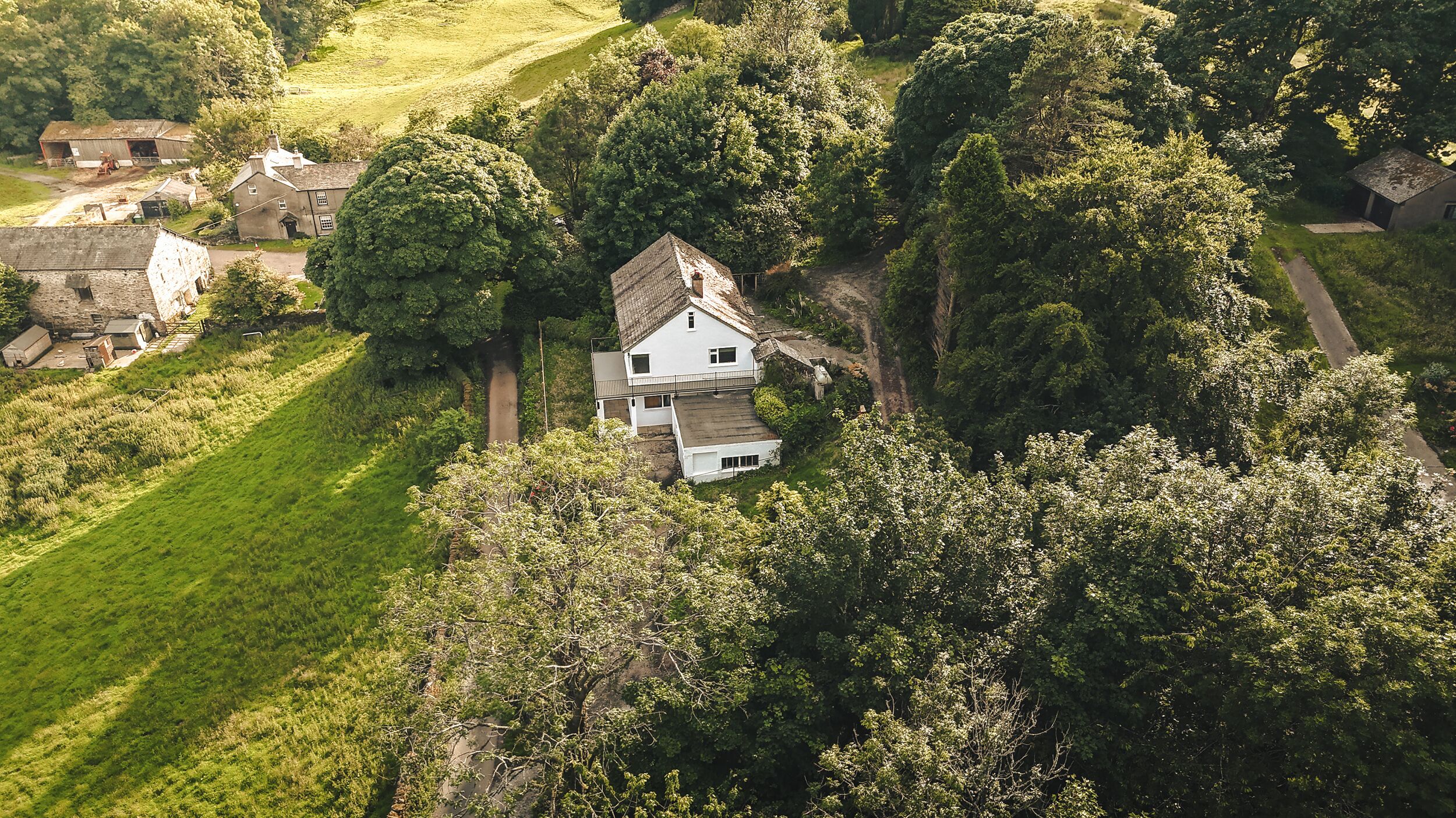 An aerial view of a house surrounded by lush greenery and trees.