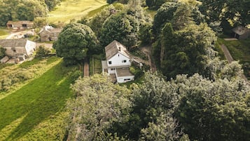 An aerial view of a house surrounded by lush greenery and trees.
