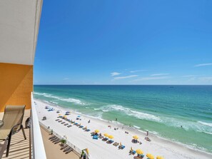 A beach view from a balcony with sun loungers and umbrellas, a clear sky, and the ocean. - ☀️Private Balcony-Panoramic Gulf Views-Pool-Treasure Island 605☀️ (Panama City Beach)