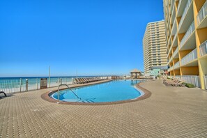 Uma área de piscina com vista clara do oceano, uma placa indicando que mergulhos não são permitidos e um edifício com varandas.