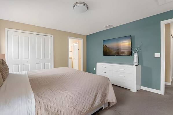 Un dormitorio con cama, cómoda, cuadro y puerta.