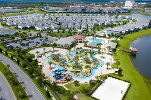 Un resort con varias villas blancas, un área de piscina central con una fuente de agua sinuosa y un puerto deportivo.