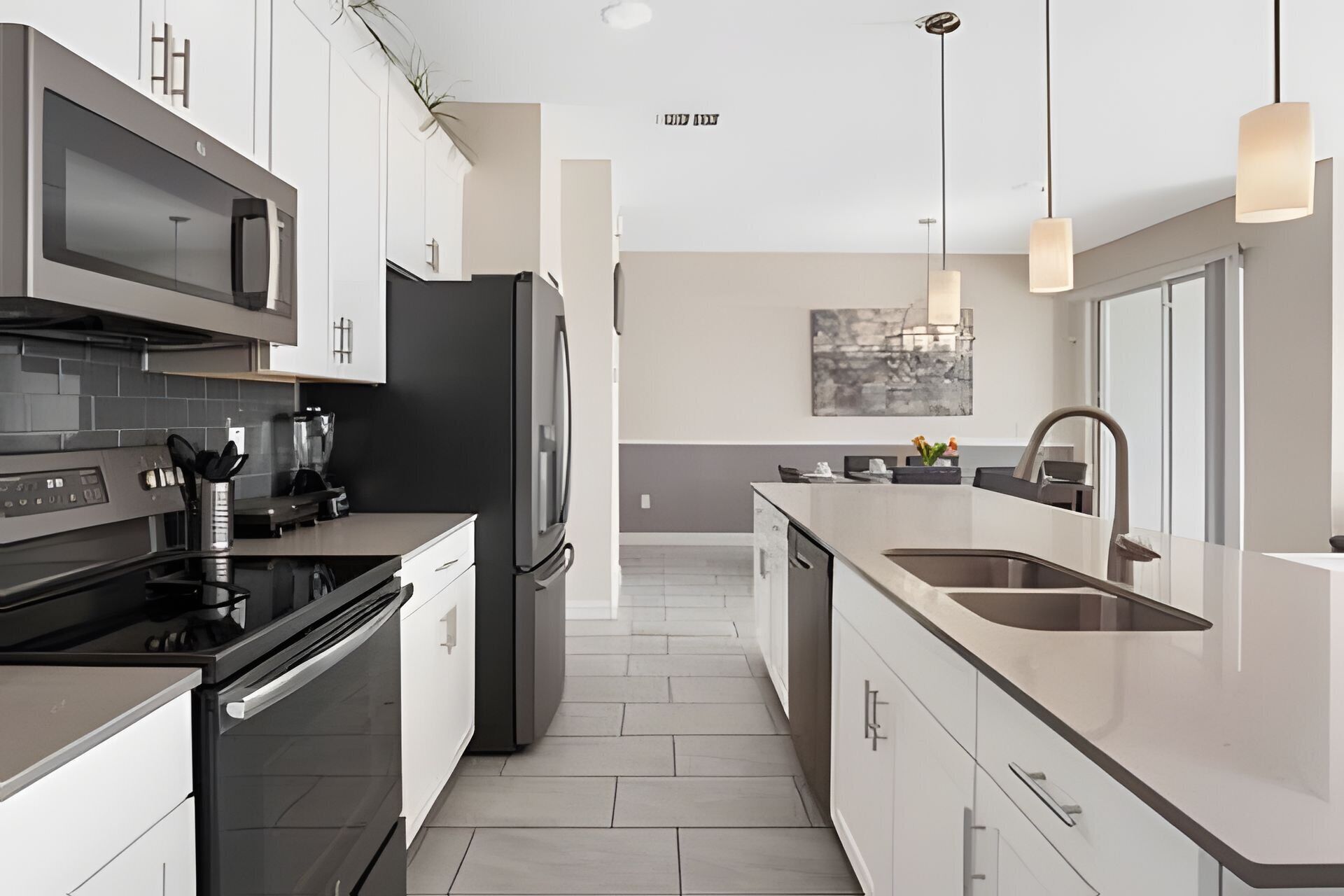 A modern kitchen with stainless steel appliances, a central island, and pendant lighting.