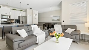Un salon moderne avec un canapé gris, une table basse blanche et un vase de fleurs.