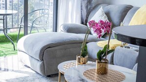 Ein modernes Wohnzimmer mit einem grauen Sofa, einem runden Couchtisch und zwei Blumentöpfen.