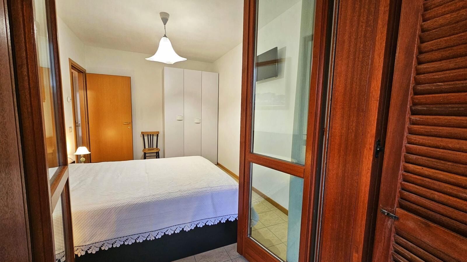Ein Schlafzimmer mit Bett, Stuhl, Kleiderschrank und Deckenleuchte.