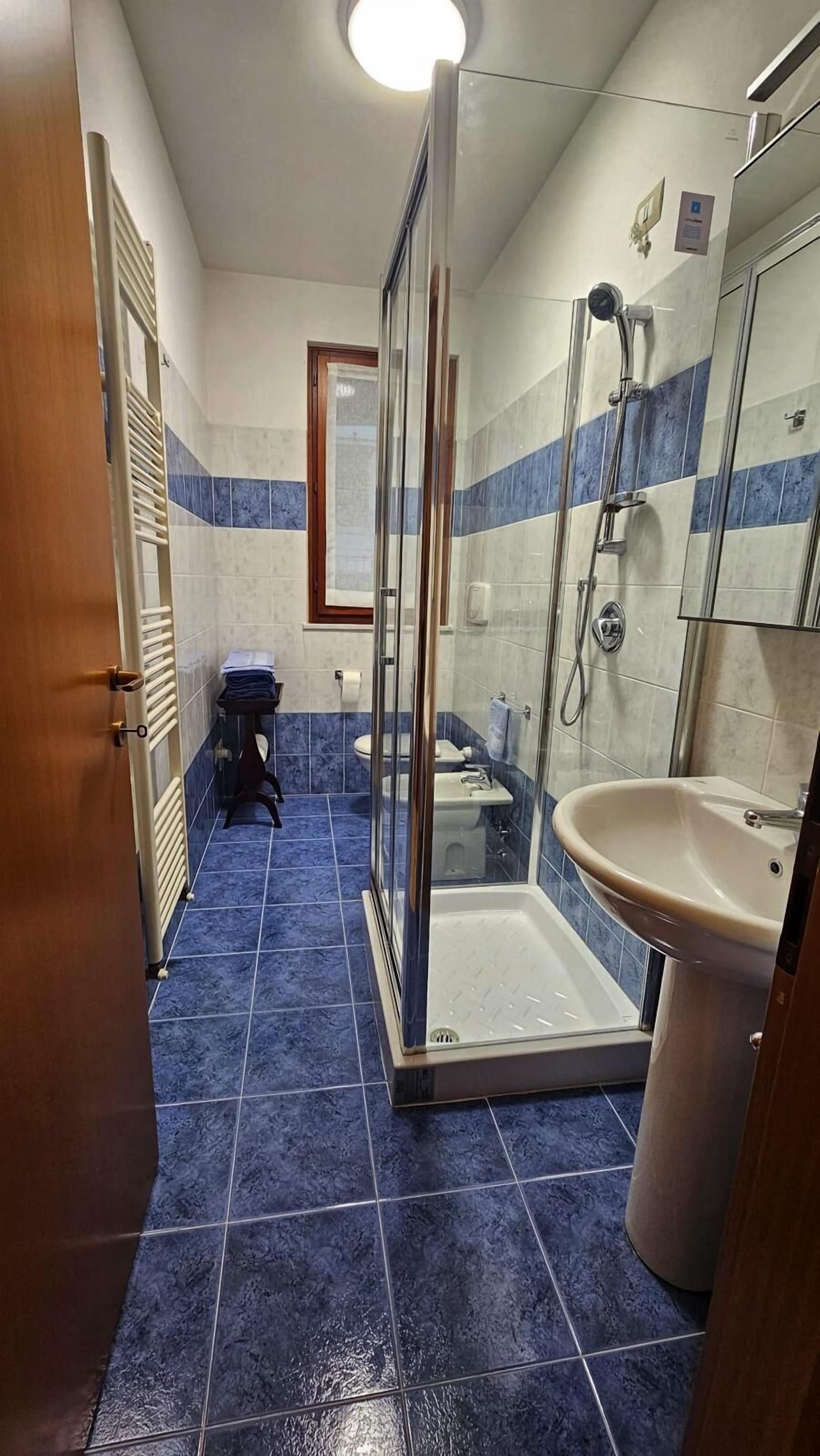 A bathroom with a glass shower enclosure, a sink, and a toilet.
