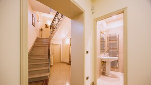 A hallway with a staircase leading to another room, a door with a radiator, and a sink. - CasAdòro - Two Bedroom Apartment, Sleeps 5 (Arezzo)