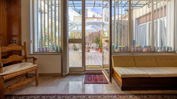 A room with a wooden bench, a sofa, and a view of an outdoor patio with a table and chairs. - CasAdòro - Two Bedroom Apartment, Sleeps 5 (Arezzo)