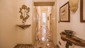 A hallway with a marble floor, a gold-framed mirror, a wooden console table with decorative items, and a framed picture on the wall. - CasAdòro - Two Bedroom Apartment, Sleeps 5 (Arezzo)
