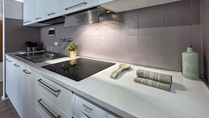 A modern kitchen with a stainless steel range hood, double sink, and integrated storage drawers.