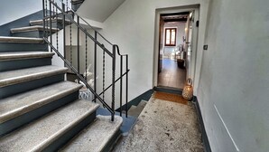 A staircase with a handrail, a carpeted landing, and a doorway leading to a room with a window and a door.