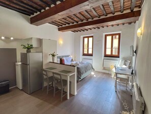 Una cocina compacta con refrigerador, una mesa de comedor con sillas y un pequeño rincón de estar con sofá.