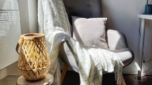 A corner room with a chair, a small table, and a lamp.