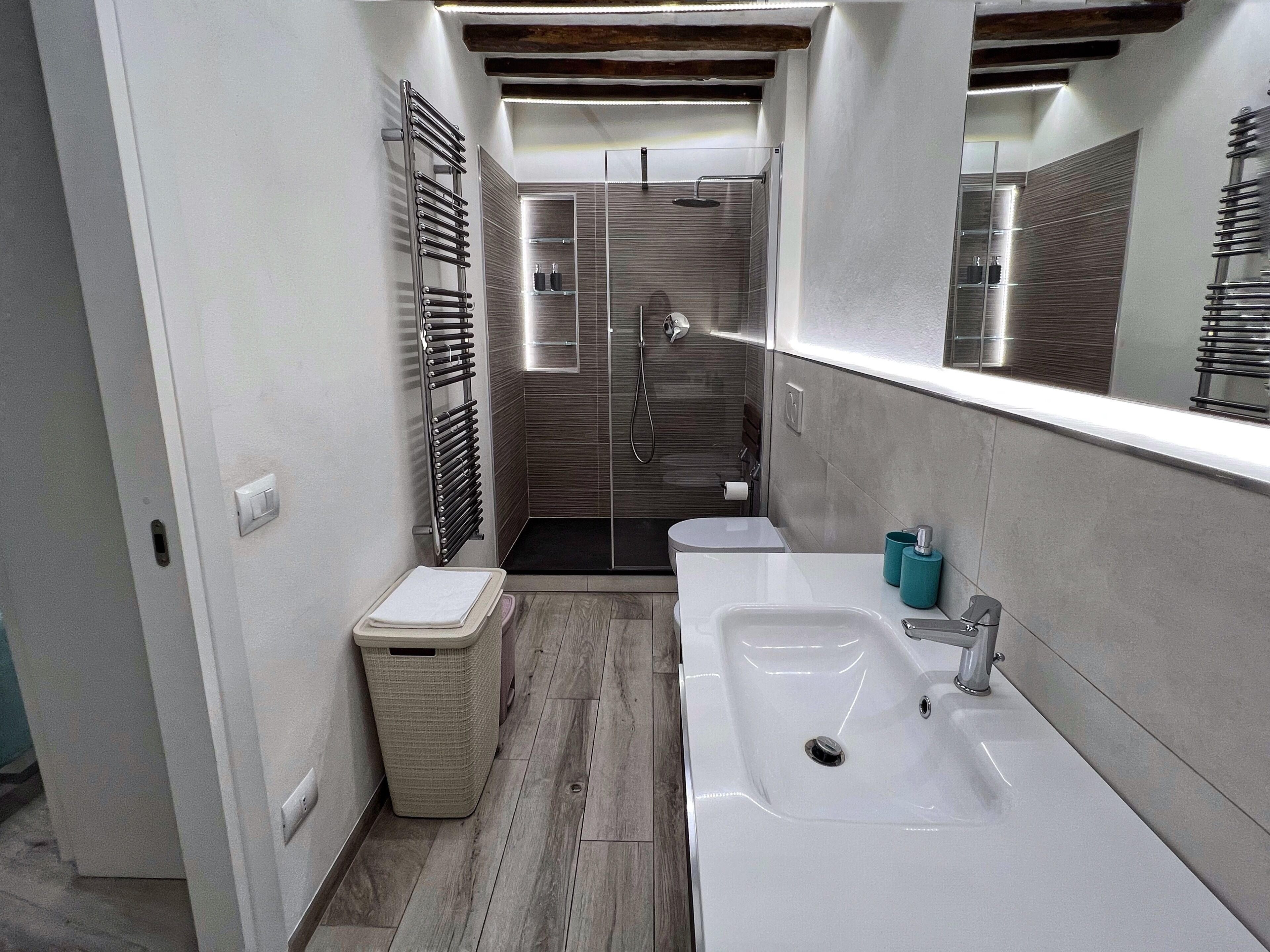 Een moderne badkamer met douche, toilet en wastafel.