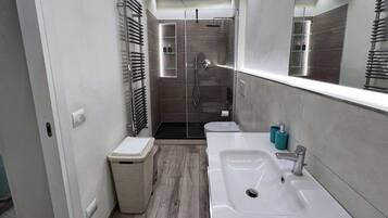 Een moderne badkamer met douche, toilet en wastafel.