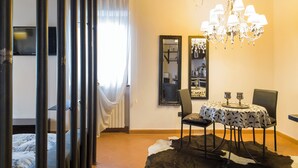 A room with a dining table, chairs, a chandelier, a mirror, and a cowhide rug.