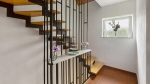 A staircase with a modern design, a window with a view, and a small shelf with vases. - Holiday Home Talblick / 160 m² / Up to 8 Guests / Garden / 2 Bathrooms / Sauerland (Schmallenberg)
