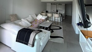 A modern, well-lit room with a large bed, a TV, and a kitchen area in the background. - Edgawater midtown beautiful 2 bedroom condo available for rent (Miami)