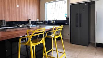 A kitchen with a wooden countertop, a black refrigerator, and yellow bar stools.