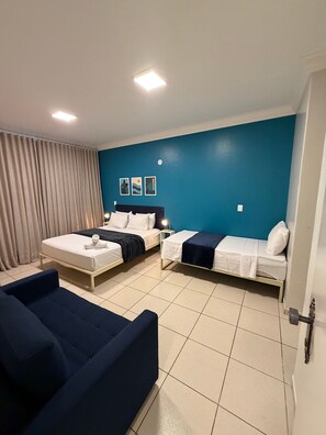 Ein Hotelzimmer mit zwei Betten, einer Couch und einem Vorhang.