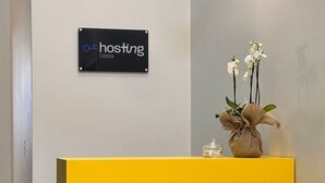 Aula, jossa on keltainen vastaanottotiski, kyltti, jossa lukee ”hosting casa”, ja valkoisia kukkia sisältävä maljakko.