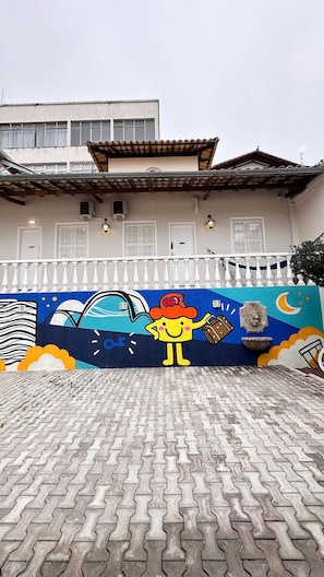 A building with a tiled roof and a mural on the wall depicting a cartoon character. - Casa Hosting (Belo Horizonte)