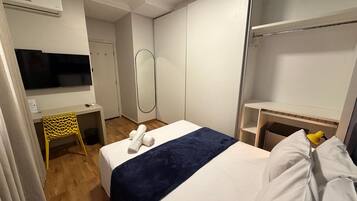 Une chambre d’hôtel équipée d’un lit, d’un bureau, d’une chaise, d’une télévision, d’un miroir et d’une armoire.