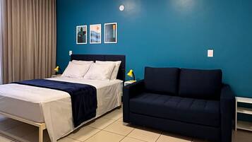 Quarto de hotel com uma cama, um sofá e uma parede azul decorativa.